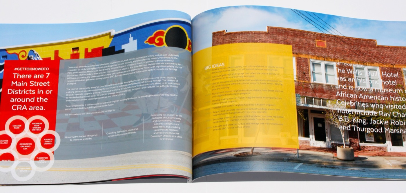 An open saddle-stitched book with a yellow page and city photography