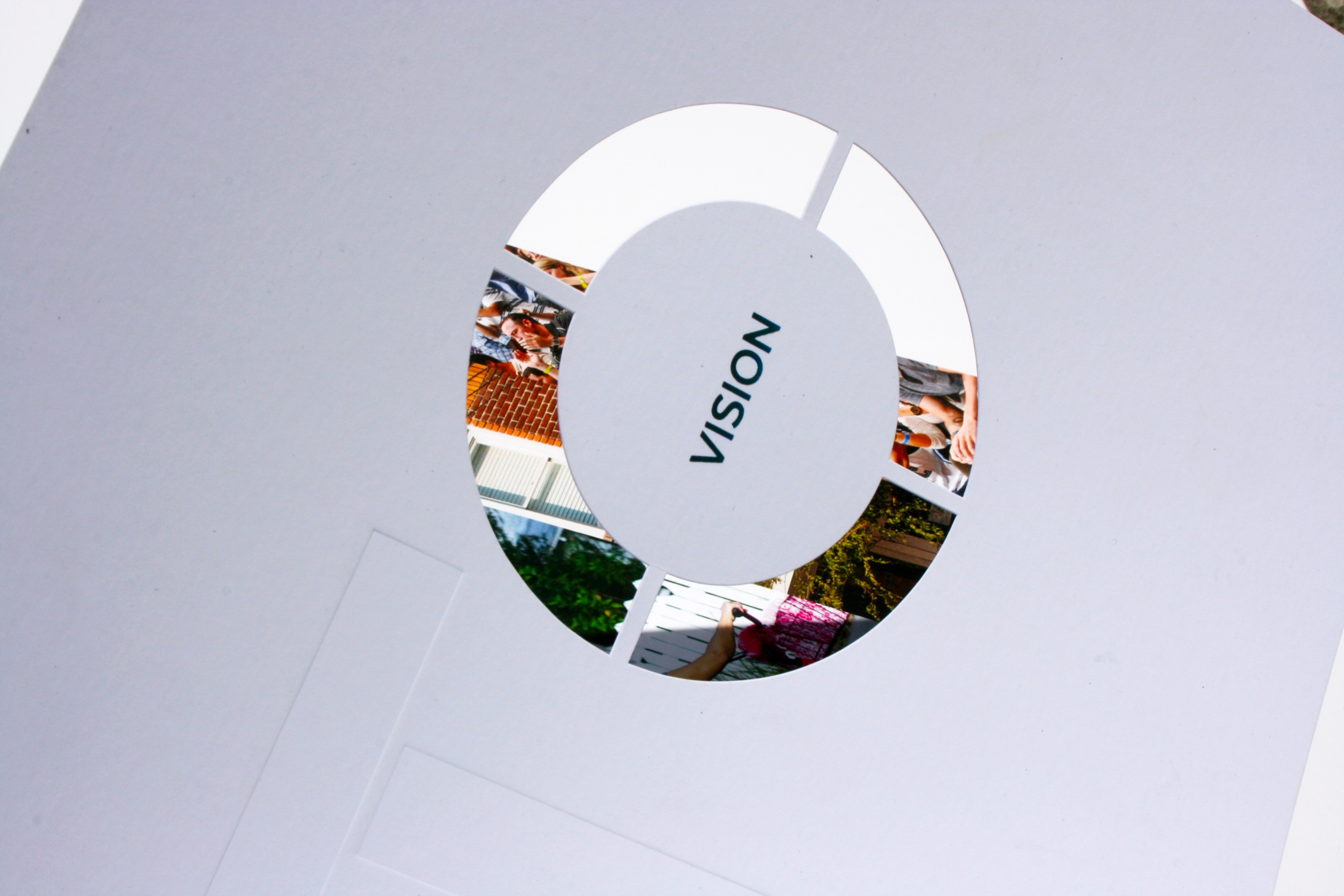 A white die-cut cover with a circle window onto city photographs, printed in our plant