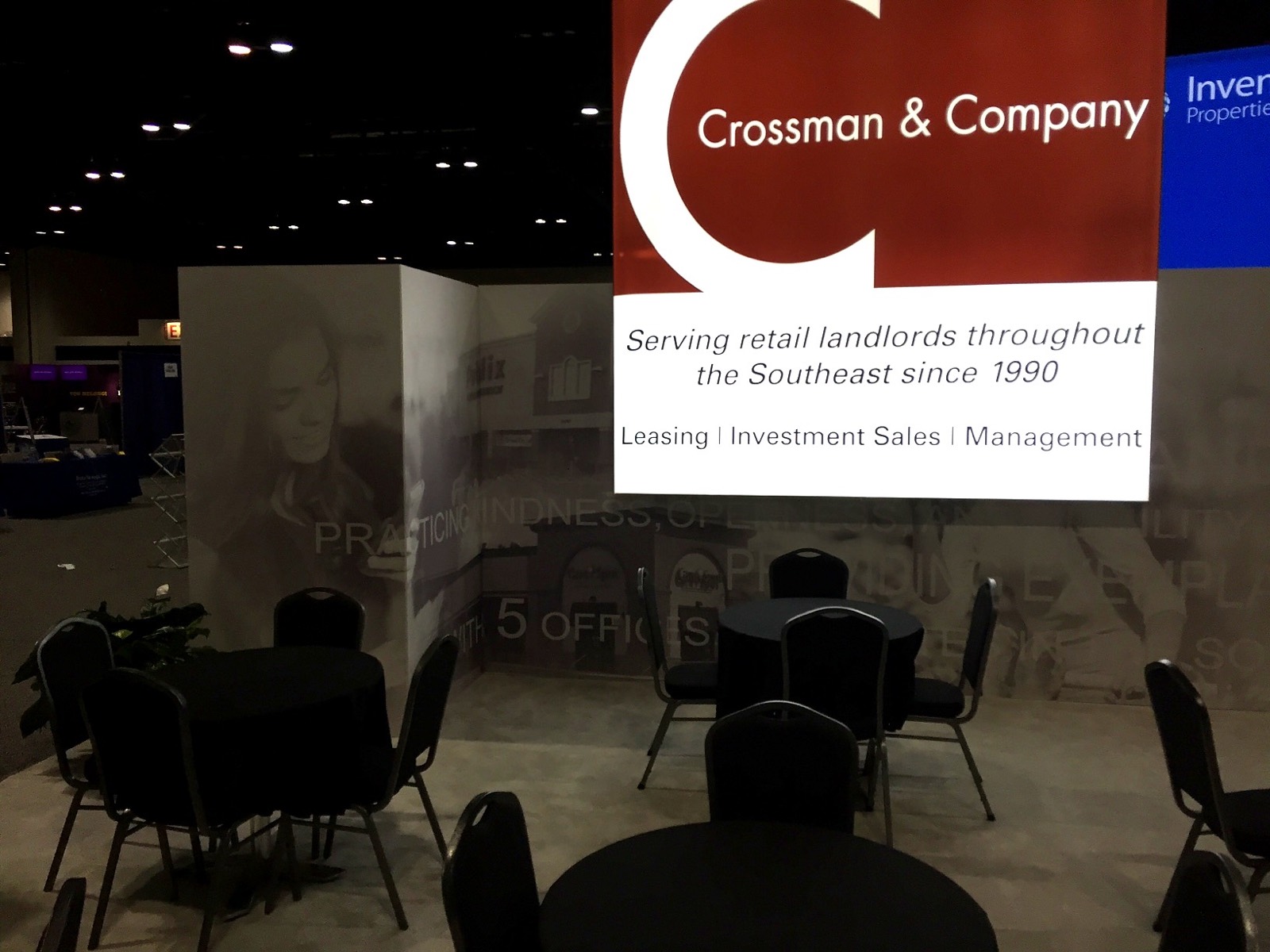 A lit Crossman and Company sign glowing above a darkened event space