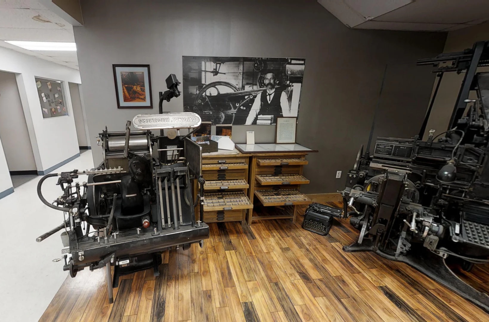 Our museum room, with an original Heidelberg letterpress, a Linotype machine and cases of hand-set type beneath a portrait of J.B. Lawton